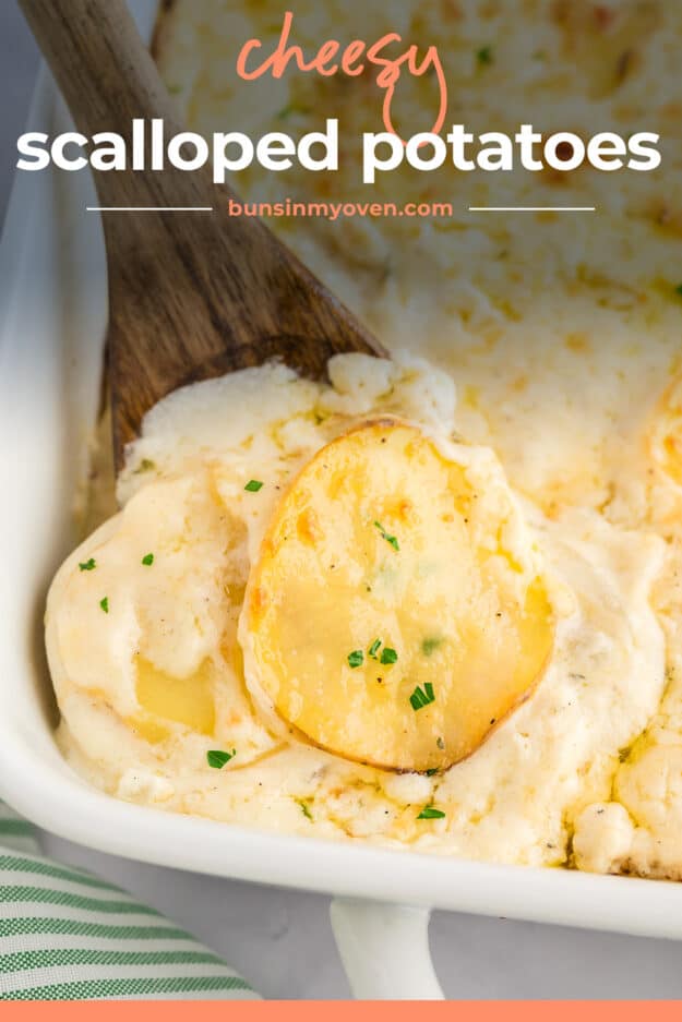 Scalloped potatoes on wooden spoon in white baking dish.