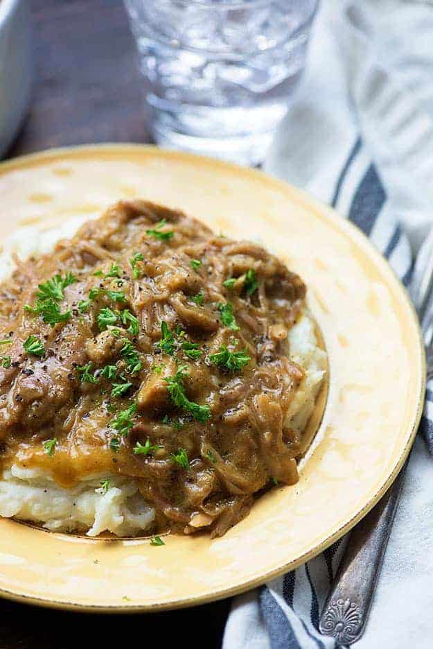 slow cooker pork roast on yellow plate with mashed potatoes