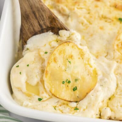 Scalloped potatoes with white cheddar in baking dish.