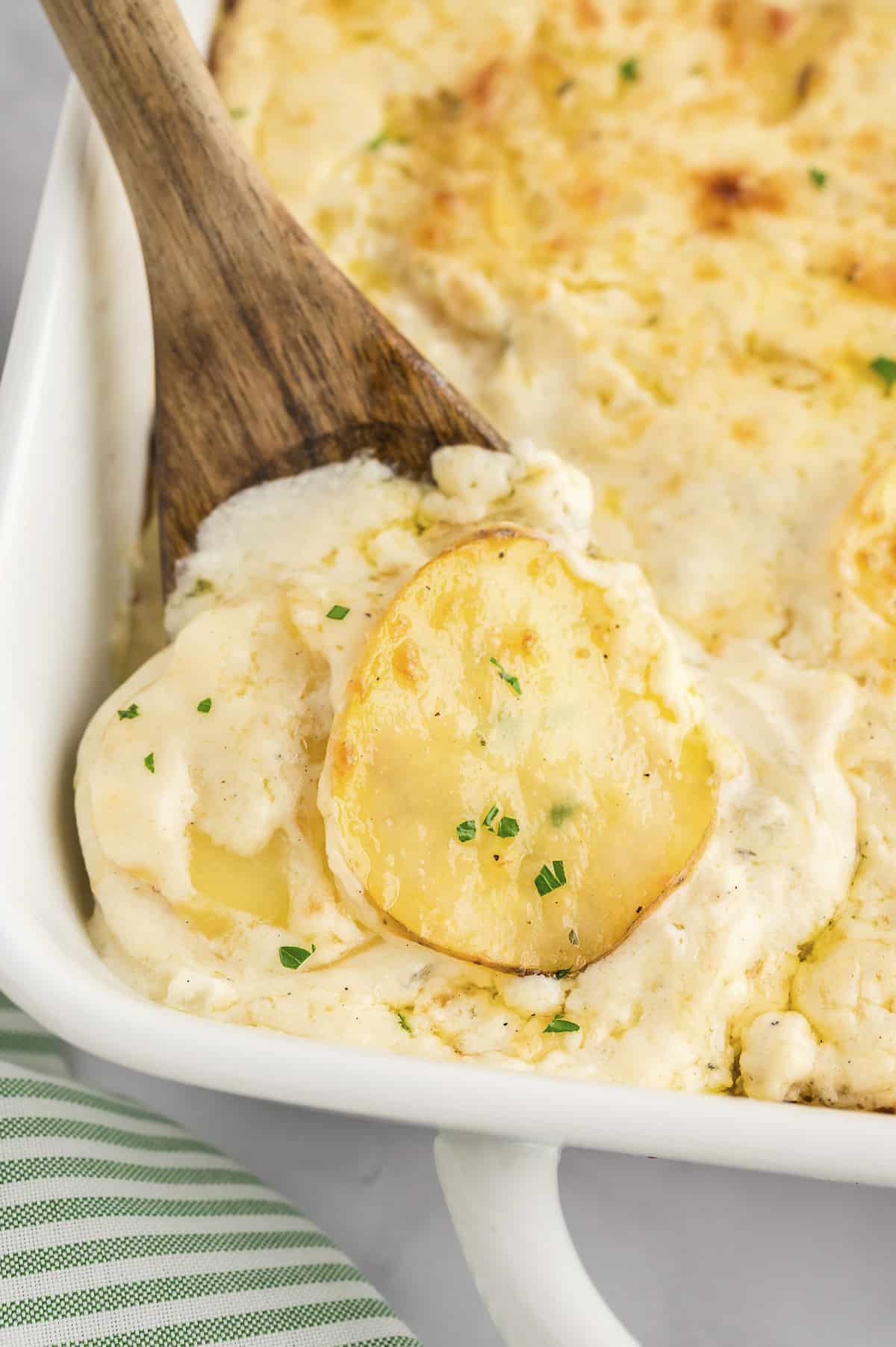 Scalloped potatoes with white cheddar in baking dish.