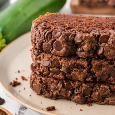 Slices of chocolate chocolate chip zucchini bread stacked on a small plate.