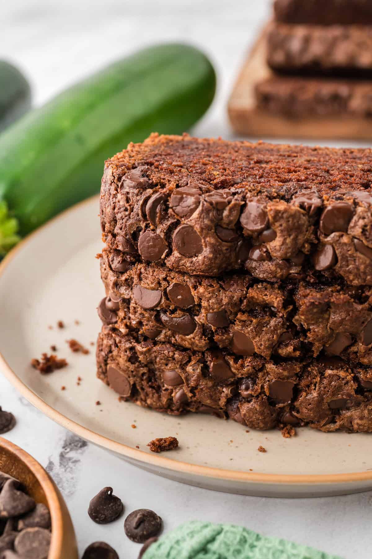 Slices of chocolate chocolate chip zucchini bread stacked on a small plate.