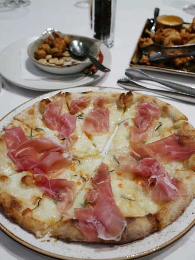 A pizza and other foods on a table.