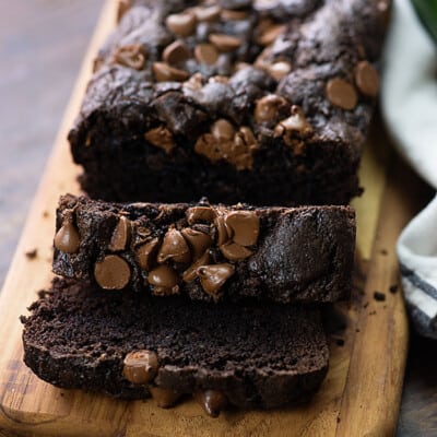 Sliced loaf of chocolate zucchini bread on a narrow wooden cutting board