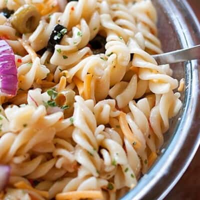 A close up of pasta salad in a clear glass bowl.