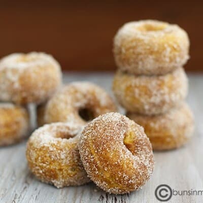 Stacked sugarcoated pumpkin doughnuts on a table