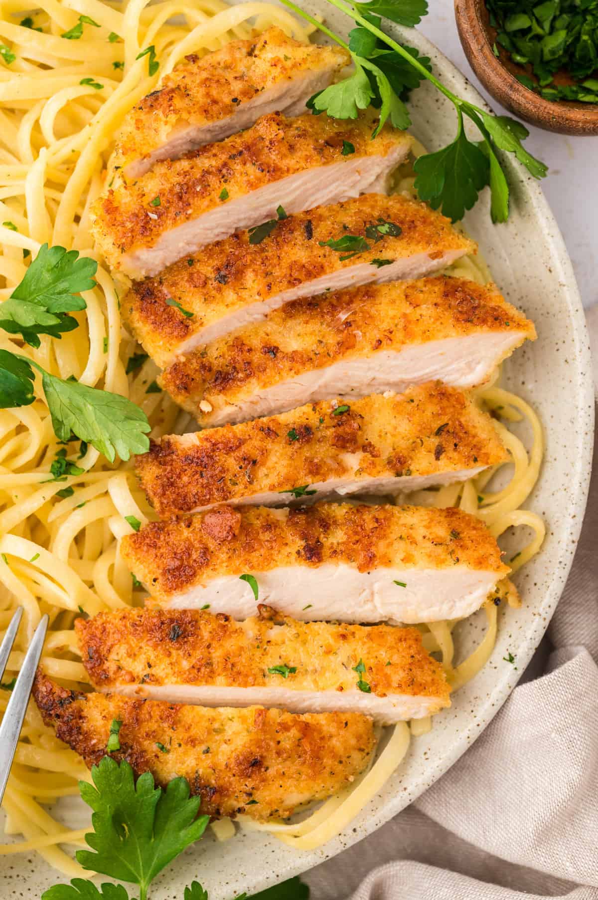 Parmesan crusted chicken sliced into strips and served with pasta.