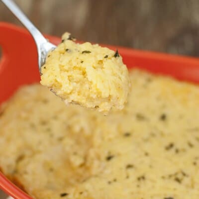 A spoonful of cheese grits being held up to the camera