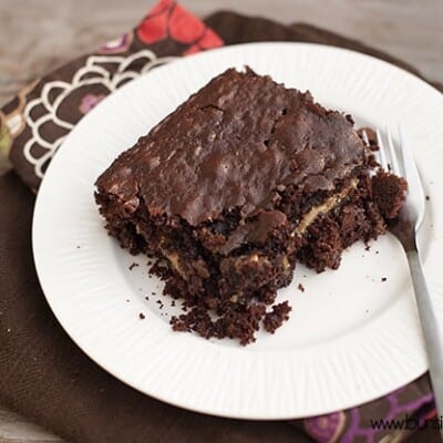 A gooey chocolate cake on a white plate with a fork