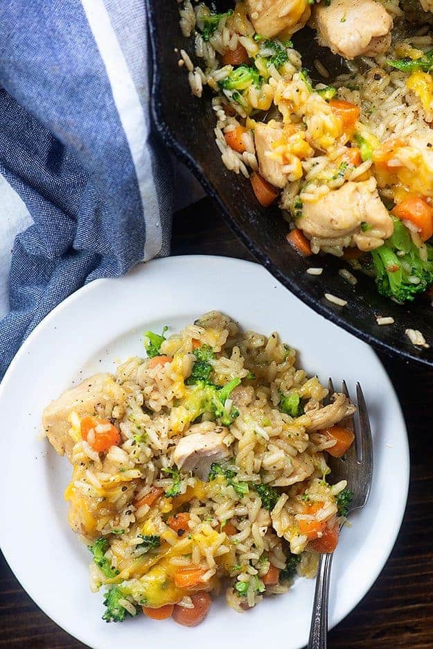 chicken and rice on a white plate next to a cast-iron skillet.