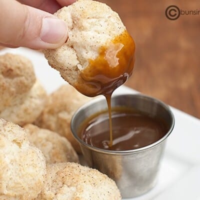 A person dipping a cinnamon biscuit ball.