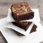 Three stacked up brownies with paper napkins in between them