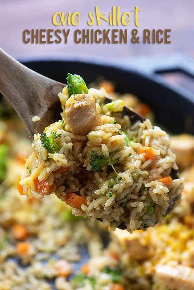 Wooden spoon holding rice and chicken over a cast-iron skillet.