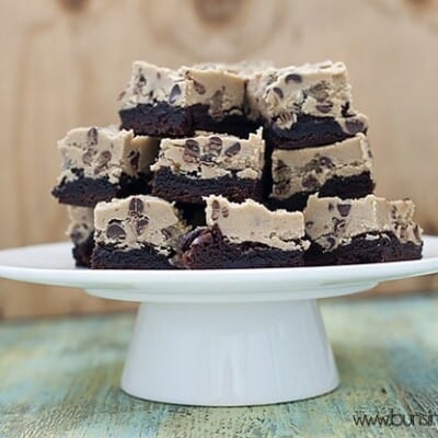 A stack of cookie dough brownies on a cake stand