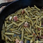 The cast iron skillet with bacon and green beans in it