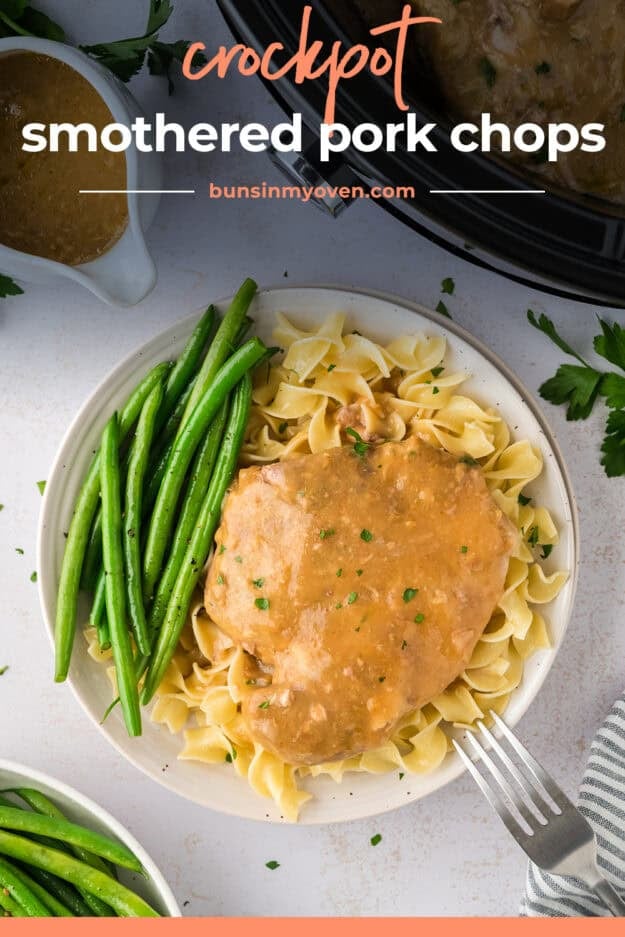 Plate full of smothered pork chops, egg noodles, and green beans.