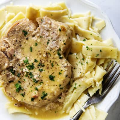 overhead view of crockpot pork chops on white plate.