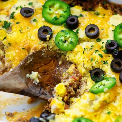 Taco casserole being scooped by a wooden spoon.