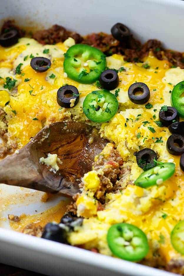 Taco casserole being scooped by a wooden spoon.