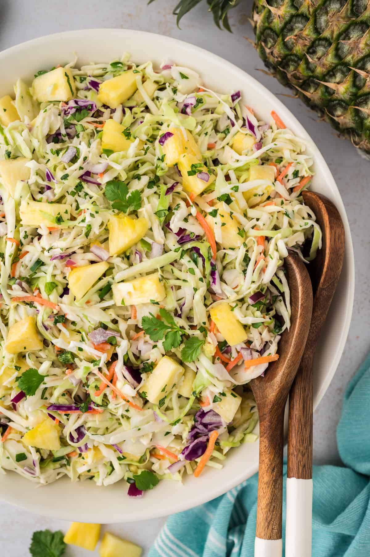 Pineapple coleslaw in serving dish with spoons.