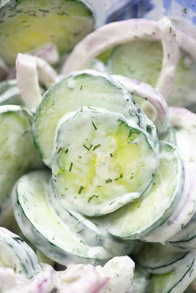 Close up of stacked cucumbers covered in a creamy sauce.