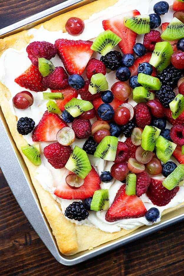 Various fruits on top of dough on a baking sheet.