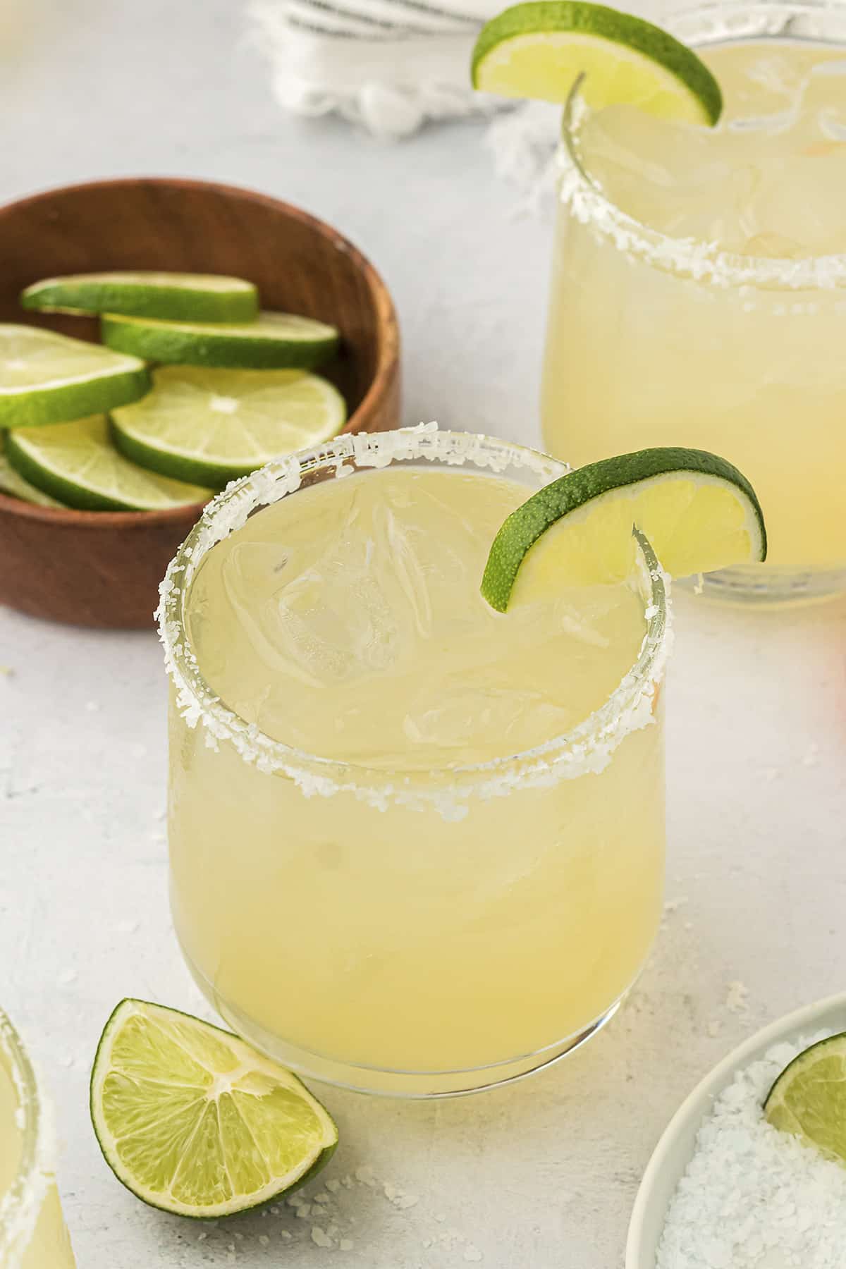 Homemade margarita on the rocks next to bowl of limes.