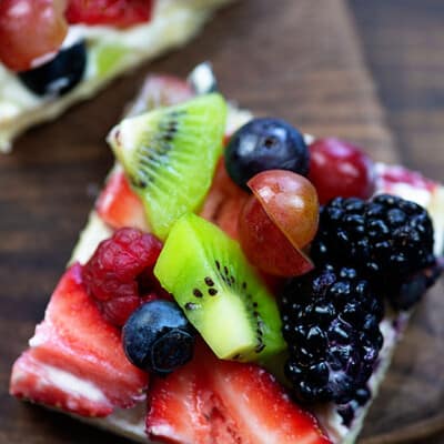 A bunch of fruits on top of a pizza square.