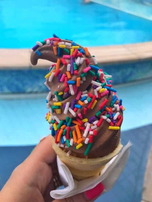A close up of a person holding a sprinkled chocolate ice cream.