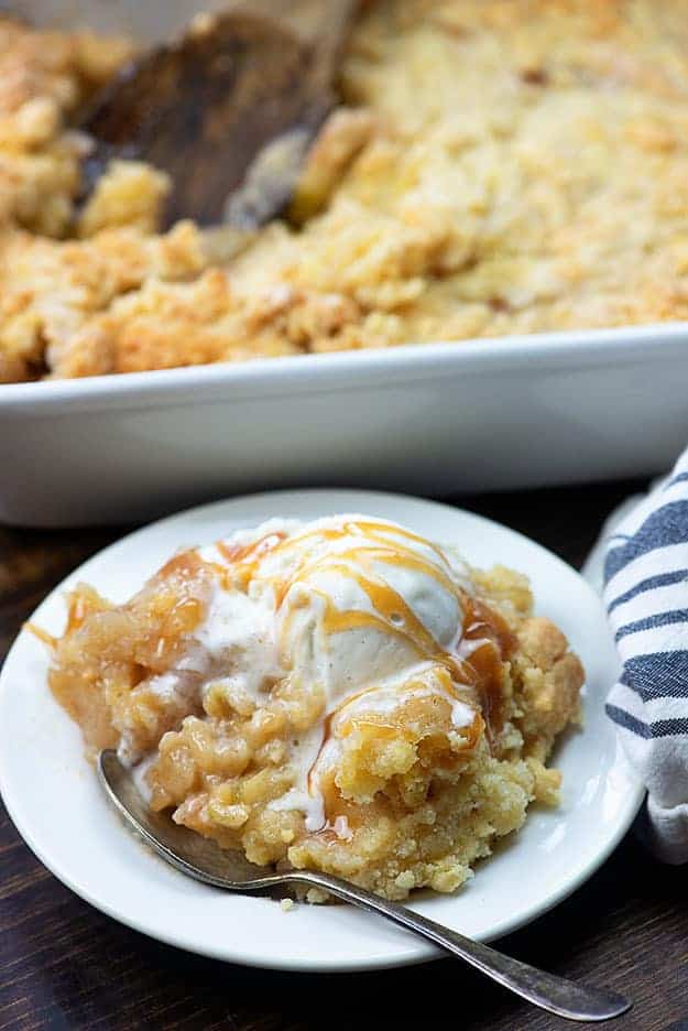 A small white plate of apple cobbler topped with caramel and ice cream.