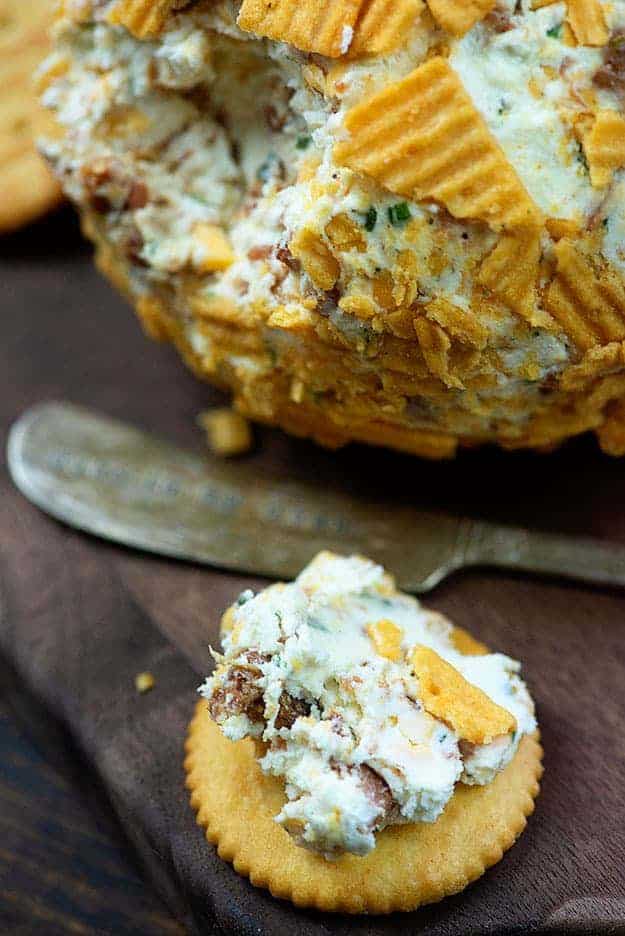 A bacon ranch spread next to a butter knife on a ritz cracker.