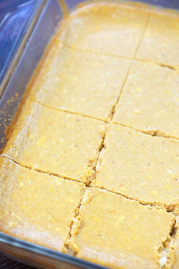 A baking sheet of cheesecake bars cut into many squares.