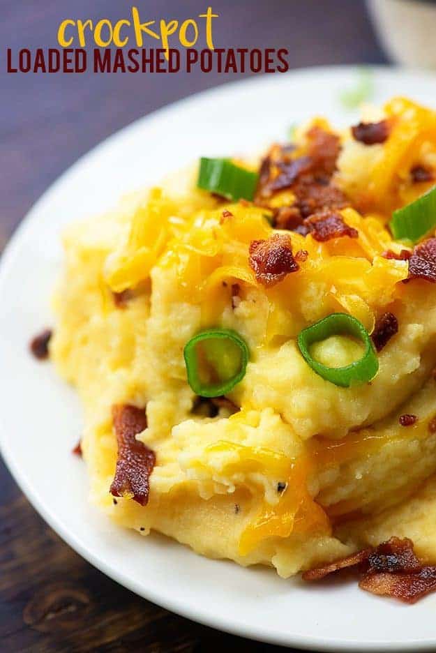 A plate of mashed potatoes with cheese, bacon, and onions on top.