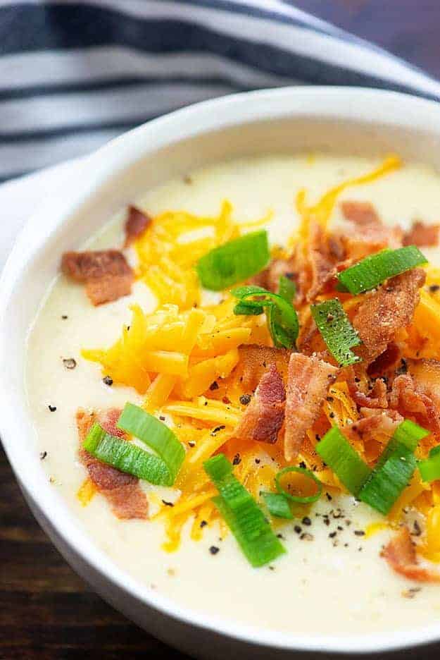 Cheese and bacon on top of a bowl of potato soup.