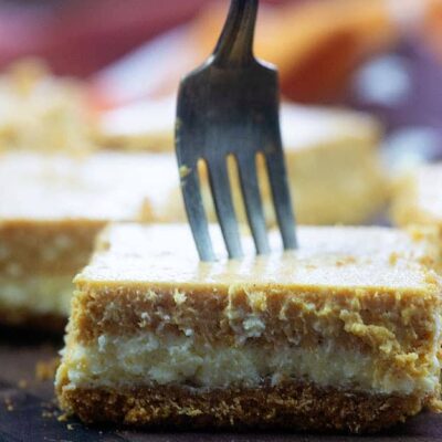 A square of cheesecake with a fork stabbing through it.