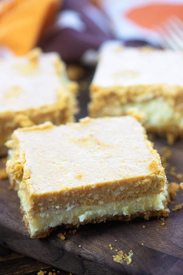 A pumpkin cheesecake square on top of a cutting board.