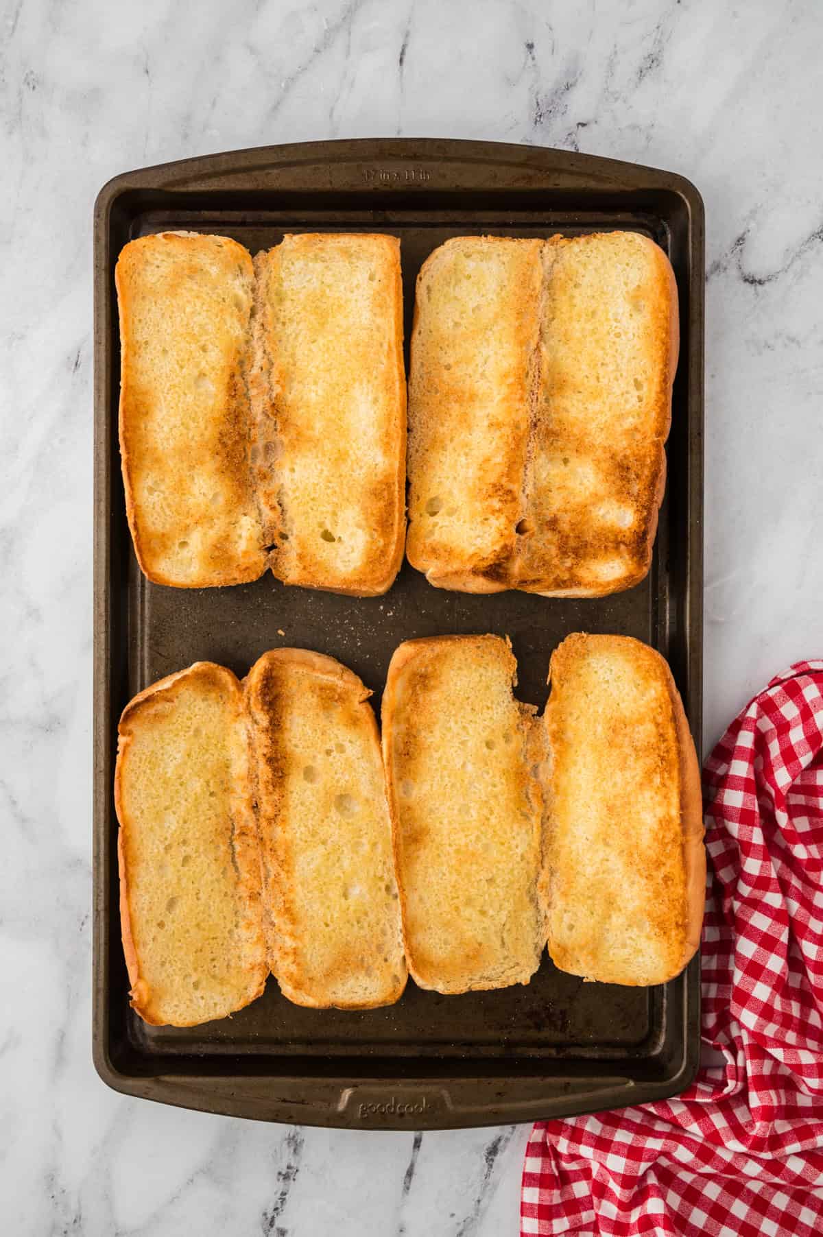 Toasted hoagie rolls on sheet pan.
