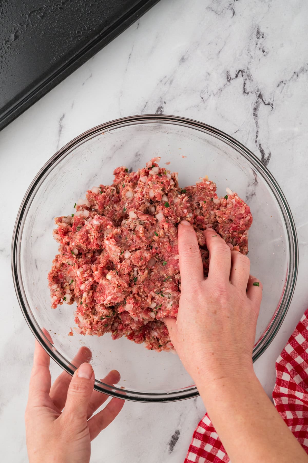 Hand mixing together meatball ingredients.