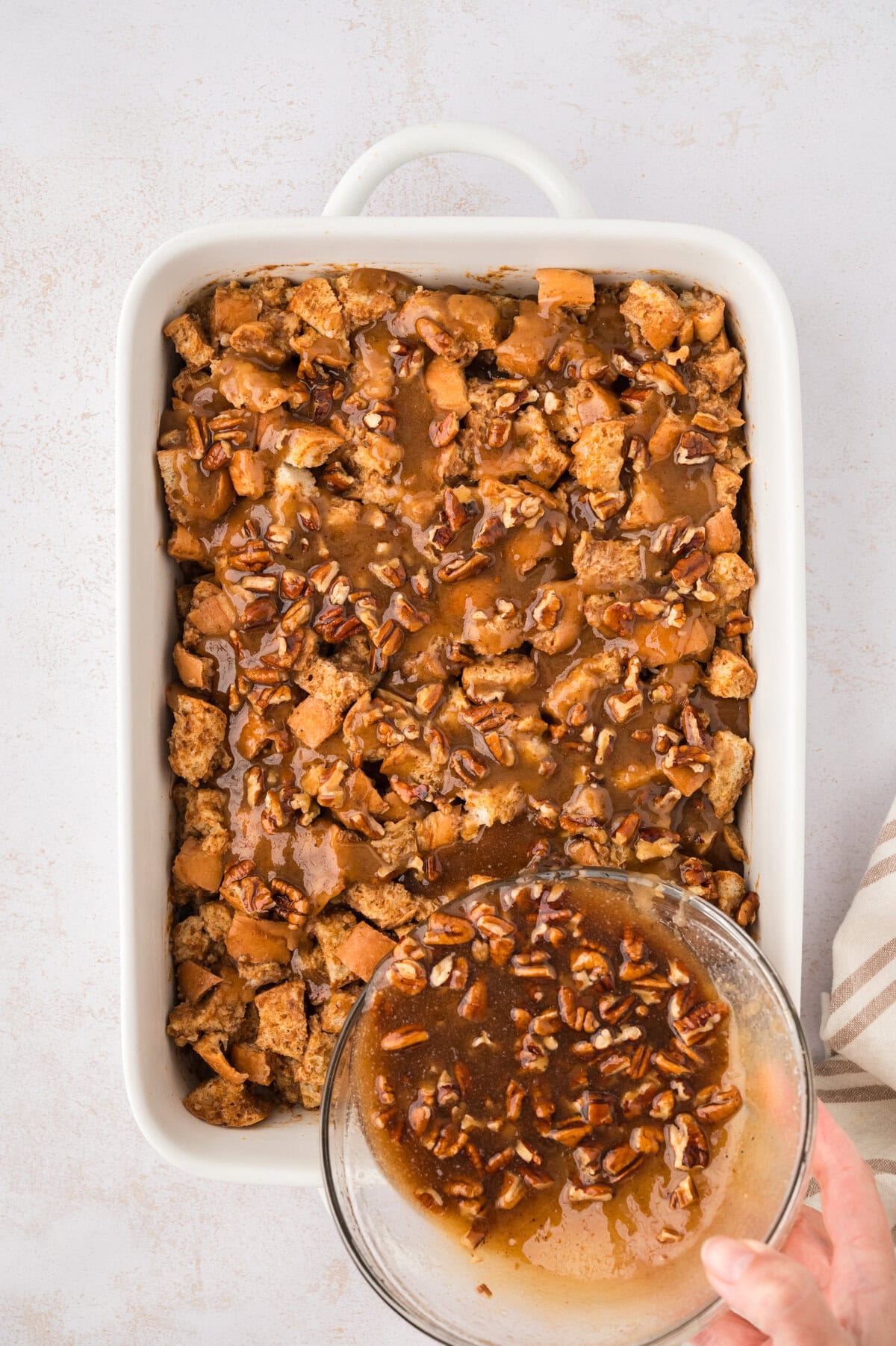 Praline mixture being poured over pumpkin french toast casserole recipe.