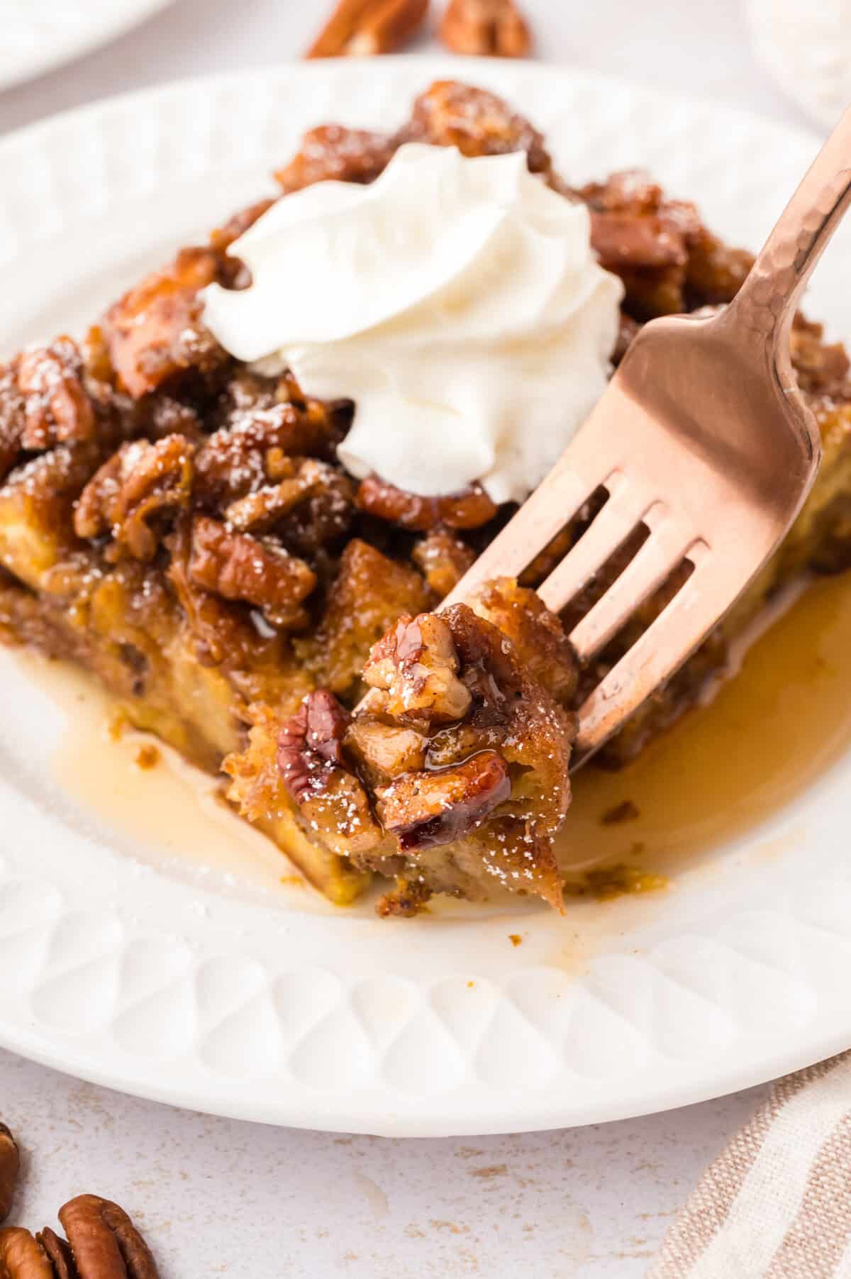 Forkful of pumpkin french toast casserole with whipped cream.