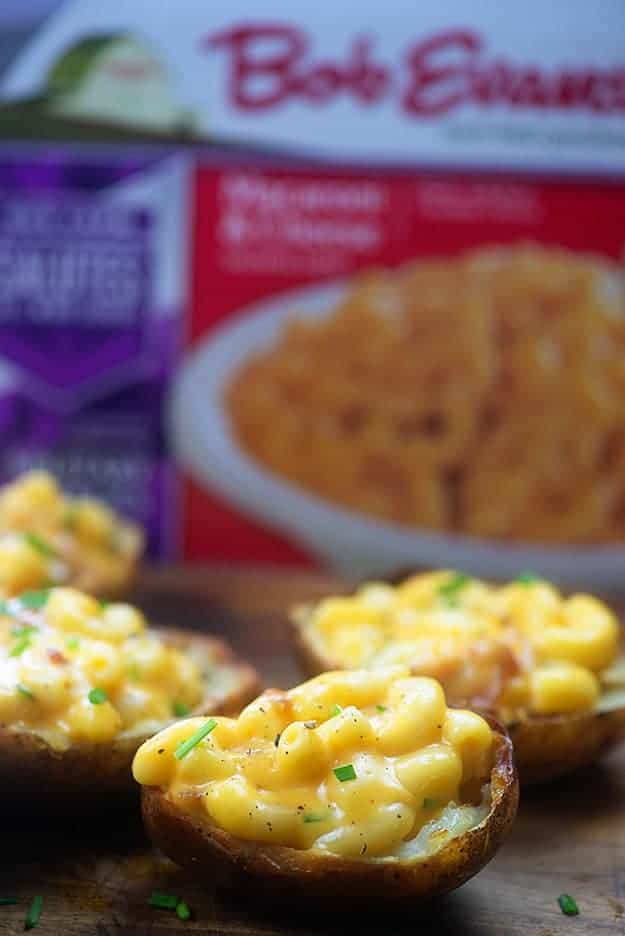 Several mac n cheese stuffed potato skins on a wooden table.