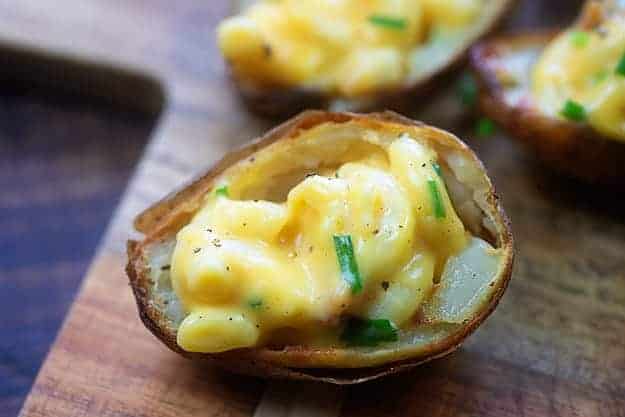 potato skins filled with macaroni and cheese on cutting board