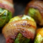 Brussel sprouts wrapped in bacon on a cutting board.