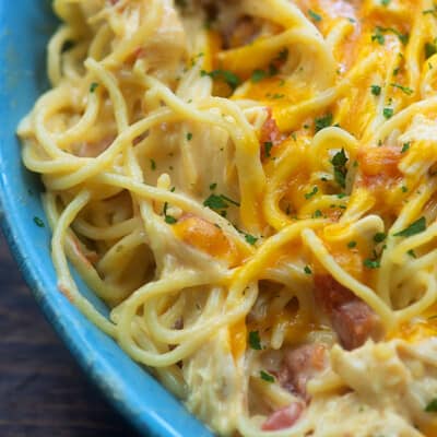 A close up of pasta in a bowl with melted cheese on top.