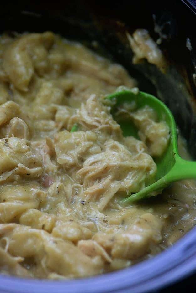 A ladle scooping chicken from a pot.