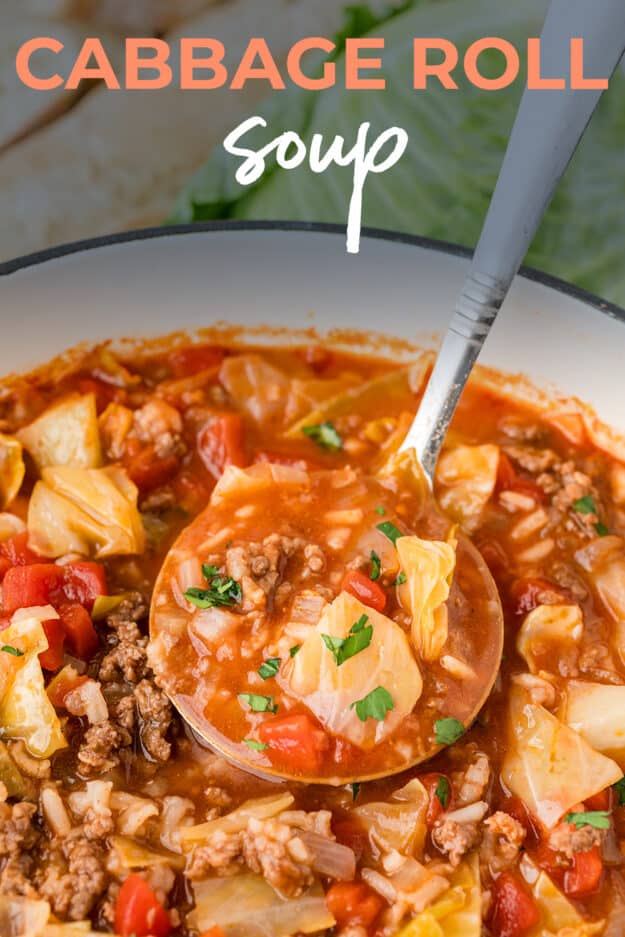 Cabbage soup on ladle over pot of soup.