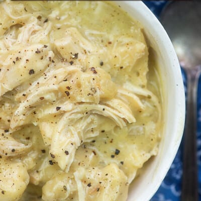 A close up of chicken and dumplings in a white bowl.