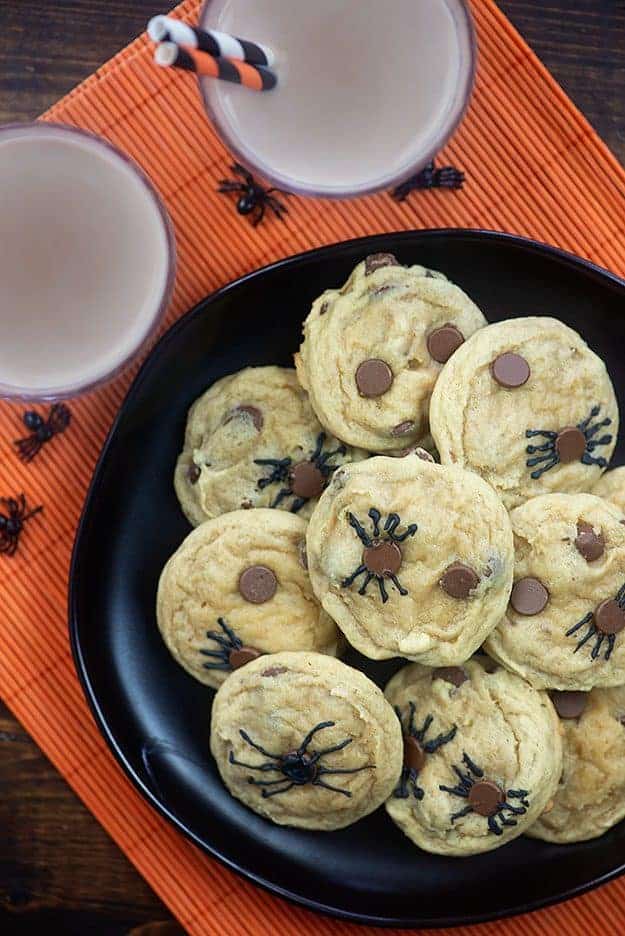 A black plate of chocolate chip spider cookies.