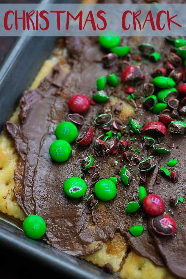 A close up of melted chocolate and m&m's on saltine crackers.