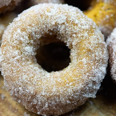 A close up of a sugar doughnut on a cutting board.